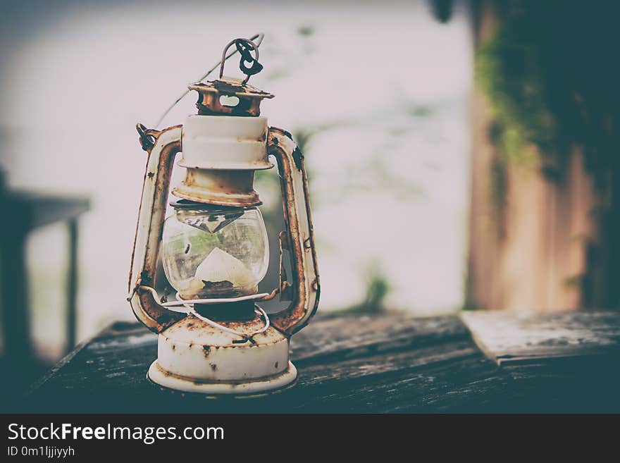 Old vintage camping lantern on wooden table. Retro gas lamp with glowing fire wick.