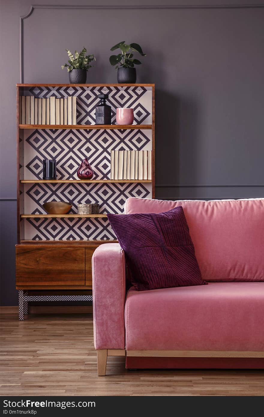 Red pillow on pink couch in retro living room interior with wood