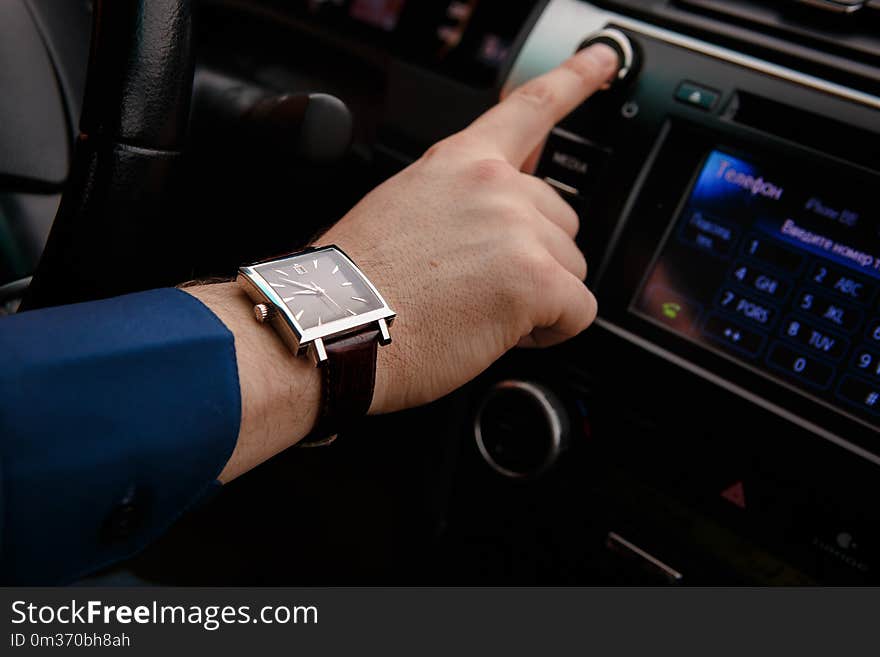 Businessman driving his car, hand on the steering wheel. Hand with golden watch. Business concept.