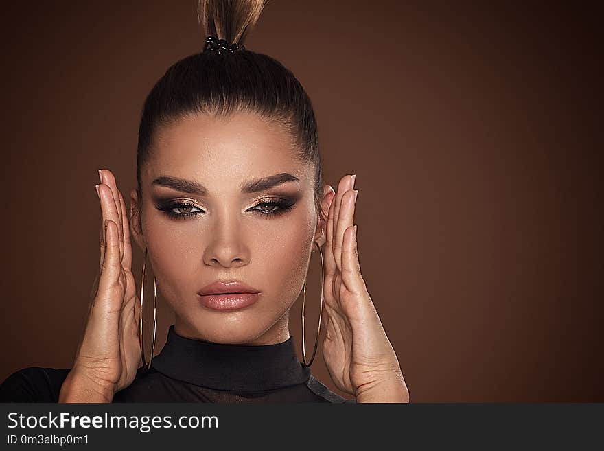 Beauty portrait. Face of beautiful woman in glamour golden makeup. Girl posing with hands near her face, looking at camera. Beauty portrait. Face of beautiful woman in glamour golden makeup. Girl posing with hands near her face, looking at camera.
