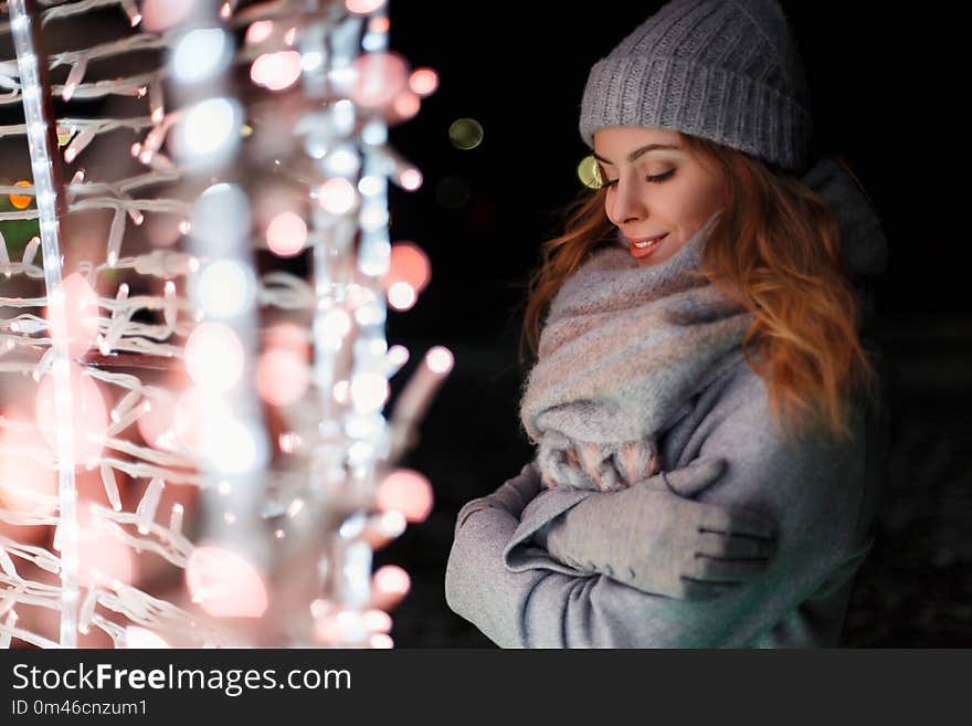 Amazing beautiful woman with a magical mood in fashion vintage knitted clothes near the lights at night on a holiday