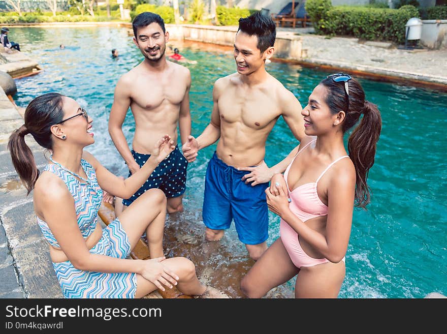 Four young and cheerful friends talking while relaxing together