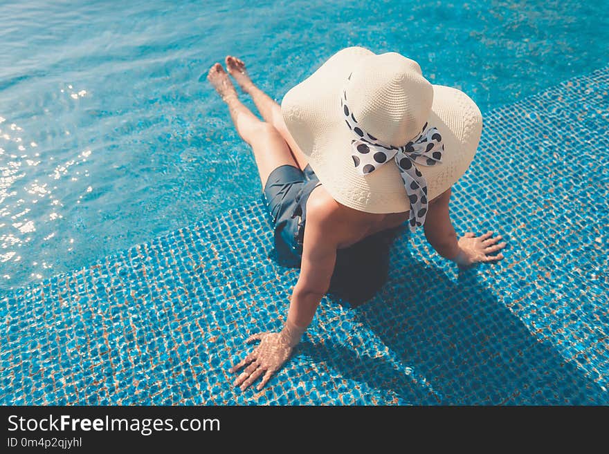 Portrait of asian woman relaxing in swimming pool with sunbathe