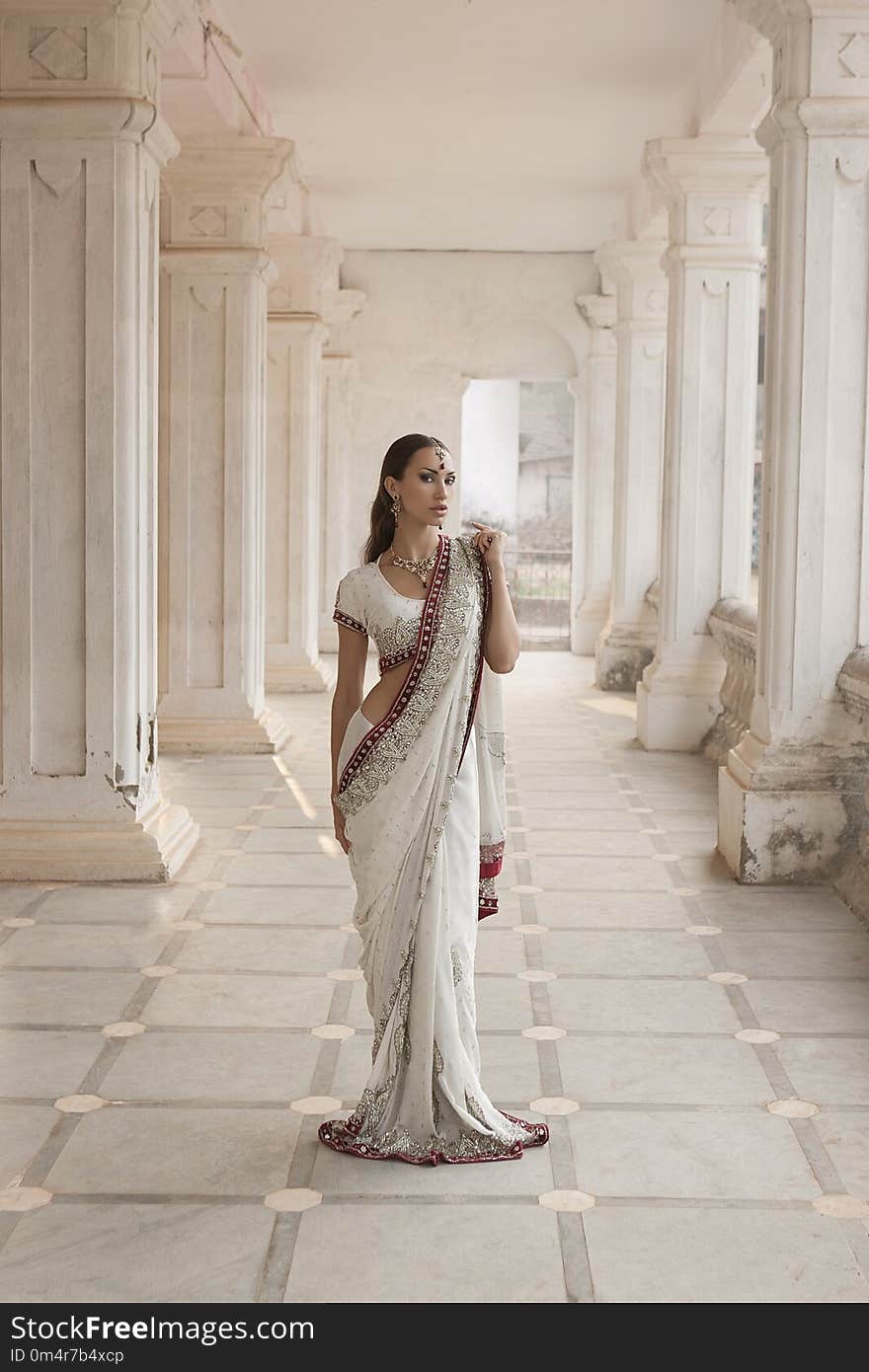 Beautiful young Indian Woman in Traditional Clothing with Bridal Makeup and Oriental Jewelry. Girl dancer in Sari posing outdoor near the Eastern Palace. Eastern fairy tale