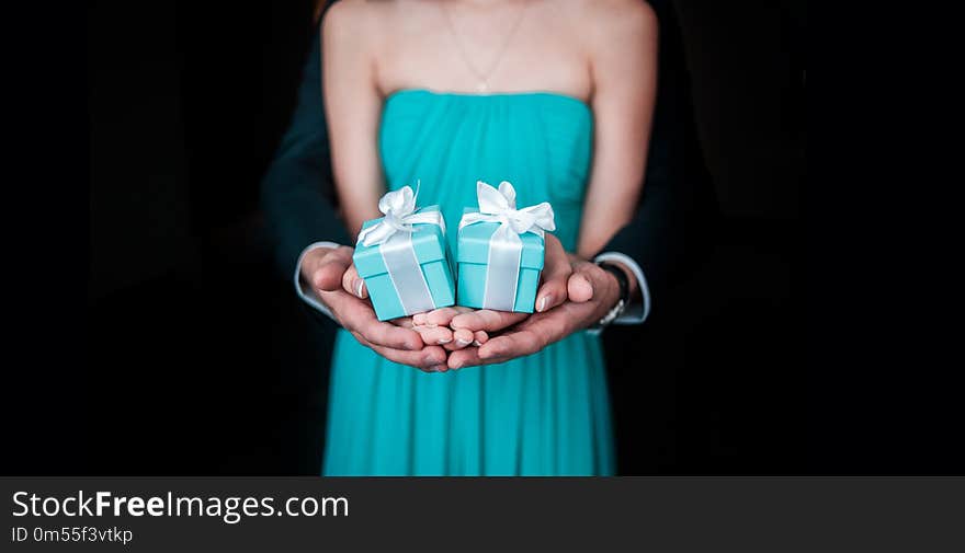 Guy with girl holding wedding gift in hands and showing in frame on the black bockground