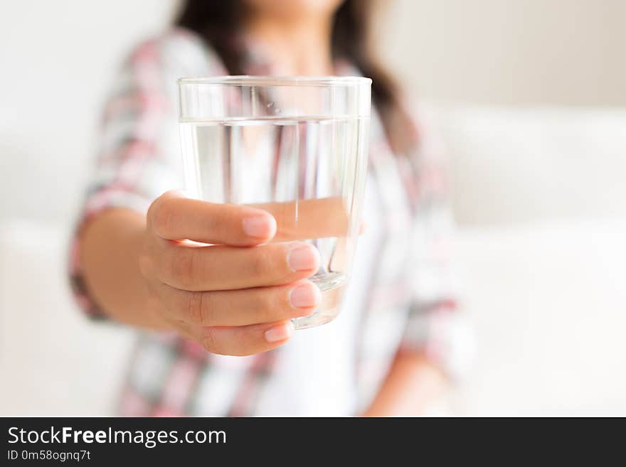 Happy beautiful young woman holding drinking water glass in her hand. Health care concept.