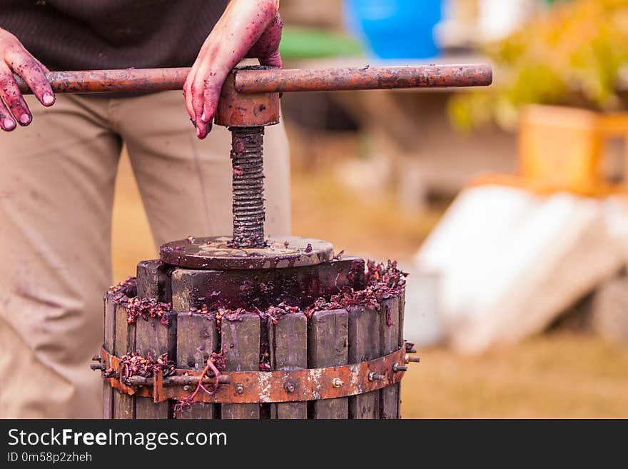 Man hands operating the press, Homemade wine production