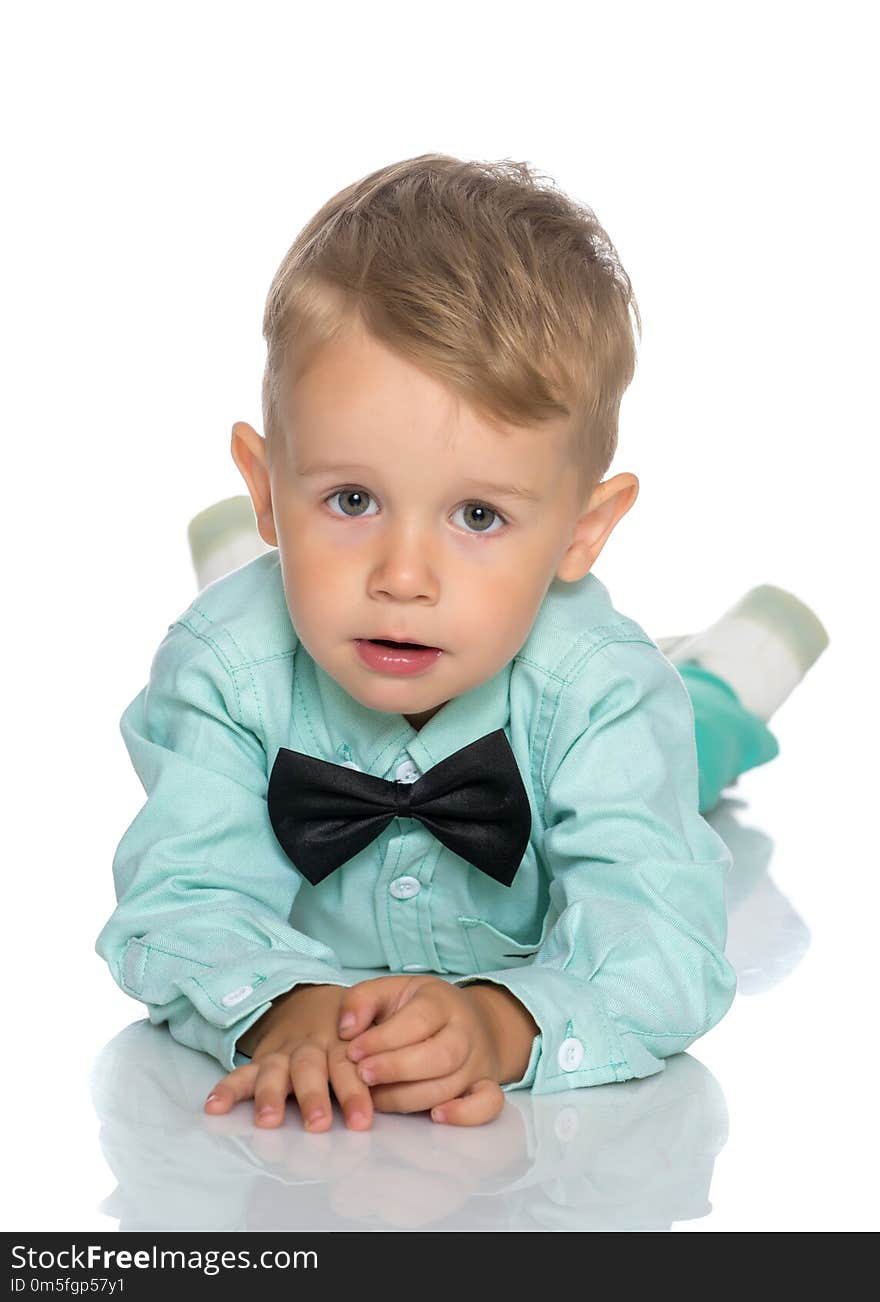 Adorable little boy lying on the floor holding his face with both hands isolated on white background. Adorable little boy lying on the floor holding his face with both hands isolated on white background