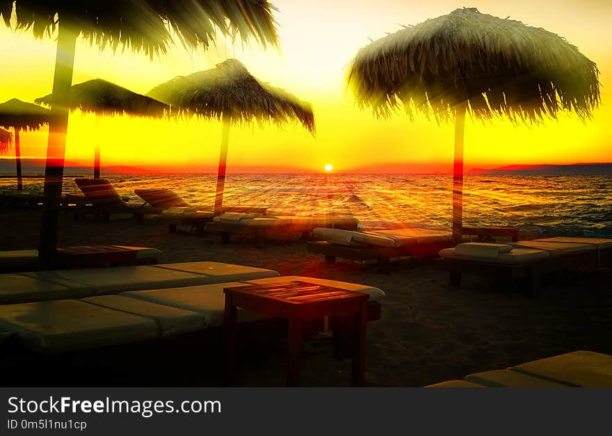 Sun rays cut through beach umbrellas at sunset sandy beach, Europe, Greece, Crete