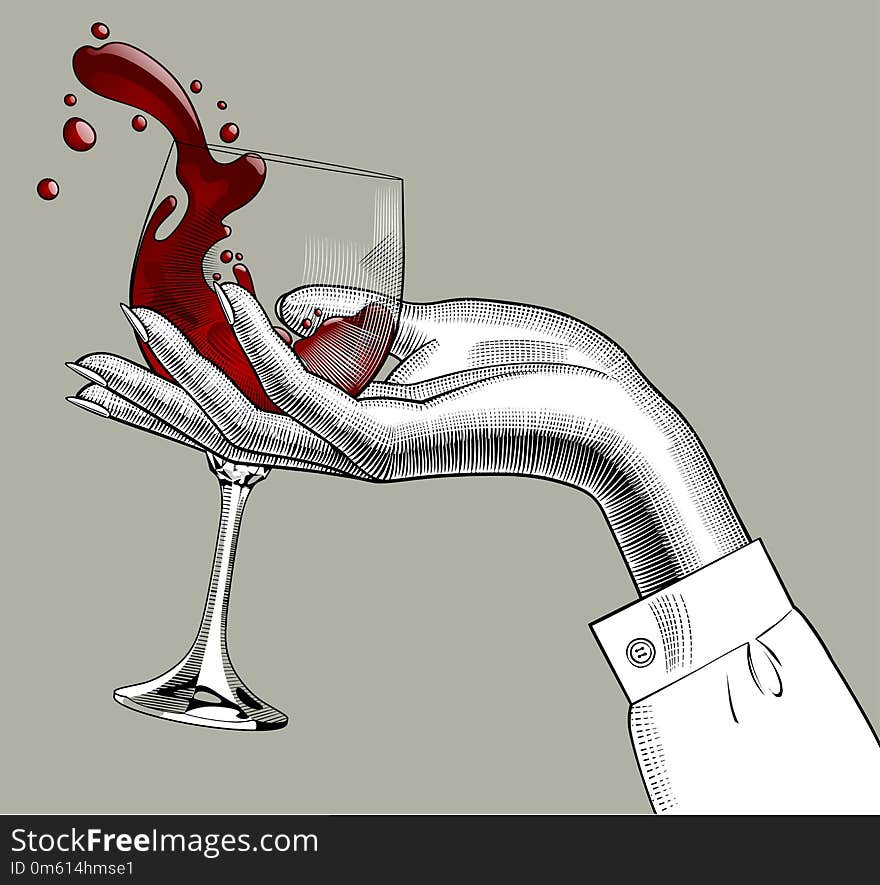 Woman`s hand holding a glass with red splashed wine