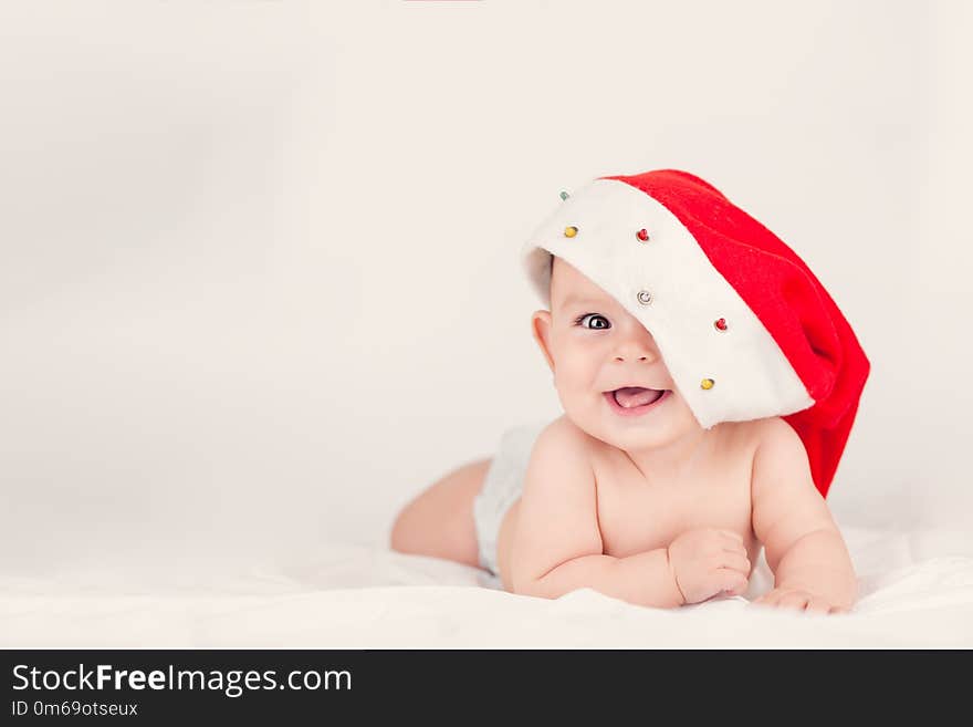 Xmas card with cute baby girl with red santa hat on beige airy briht background with copy space