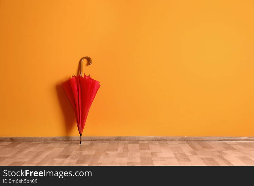 Beautiful umbrella on floor near color wall with space for design