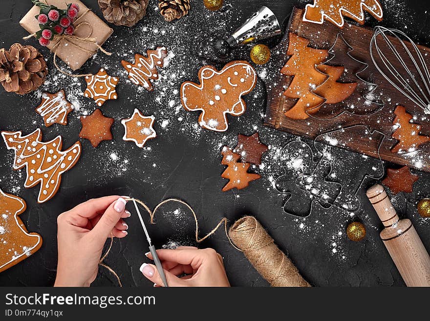 Christmas gift gingerbread on dark background. Christmas Gingerbread Cookies. Biscuits in festive packaging. Woman is packaging Christmas gingerbread cookies with icing sugar. Holiday, celebration and cooking concept. Christmas preparations concept. Top view. Christmas gift gingerbread on dark background. Christmas Gingerbread Cookies. Biscuits in festive packaging. Woman is packaging Christmas gingerbread cookies with icing sugar. Holiday, celebration and cooking concept. Christmas preparations concept. Top view