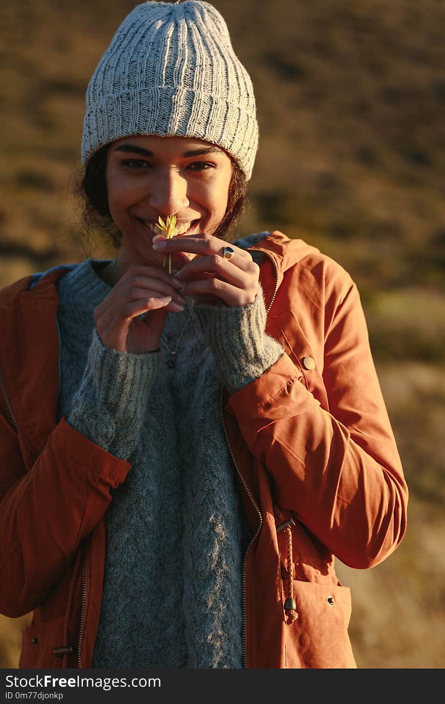 Woman in winter wear smelling a flower on mountain