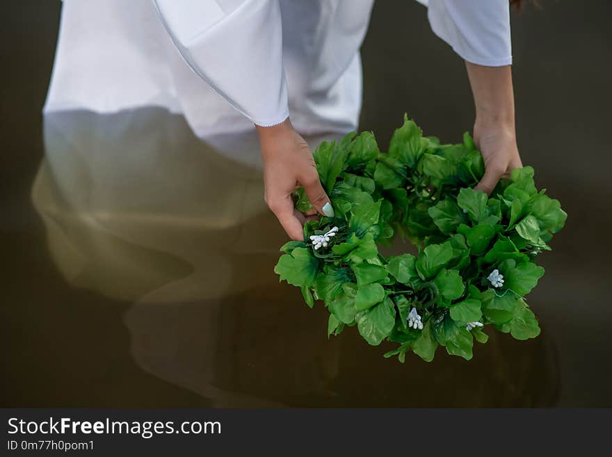 Close-up of woman in white dress in the water. Art Woman with wreath in river. Wet witch Girl in the lake