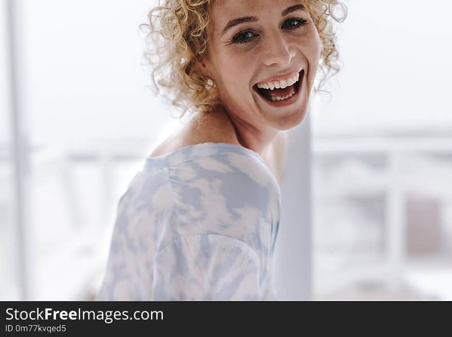 Close of a woman at home smiling. Woman with curly brown hair laughing. Close of a woman at home smiling. Woman with curly brown hair laughing.