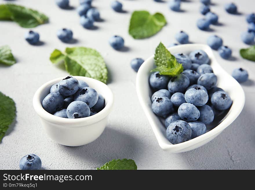 Juicy blueberries and green leaves on color table