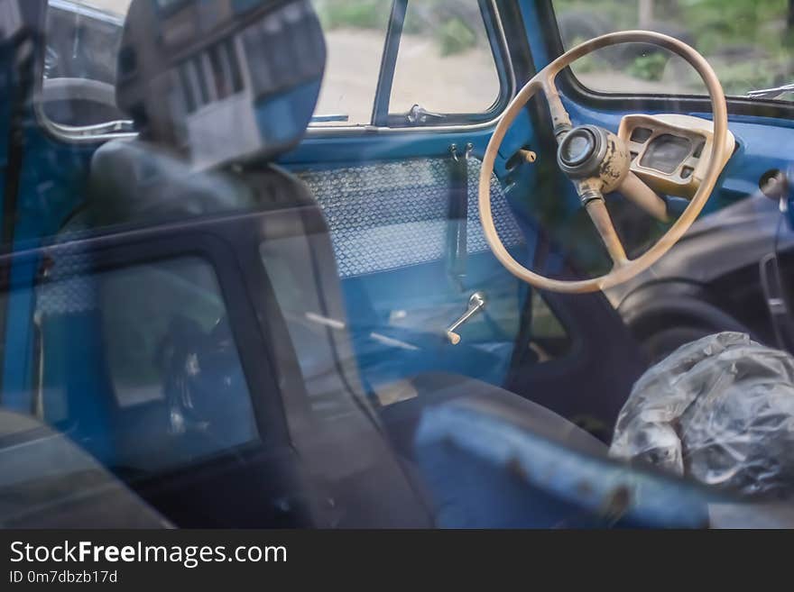 Side part of bright blue old automobile with wheel in window