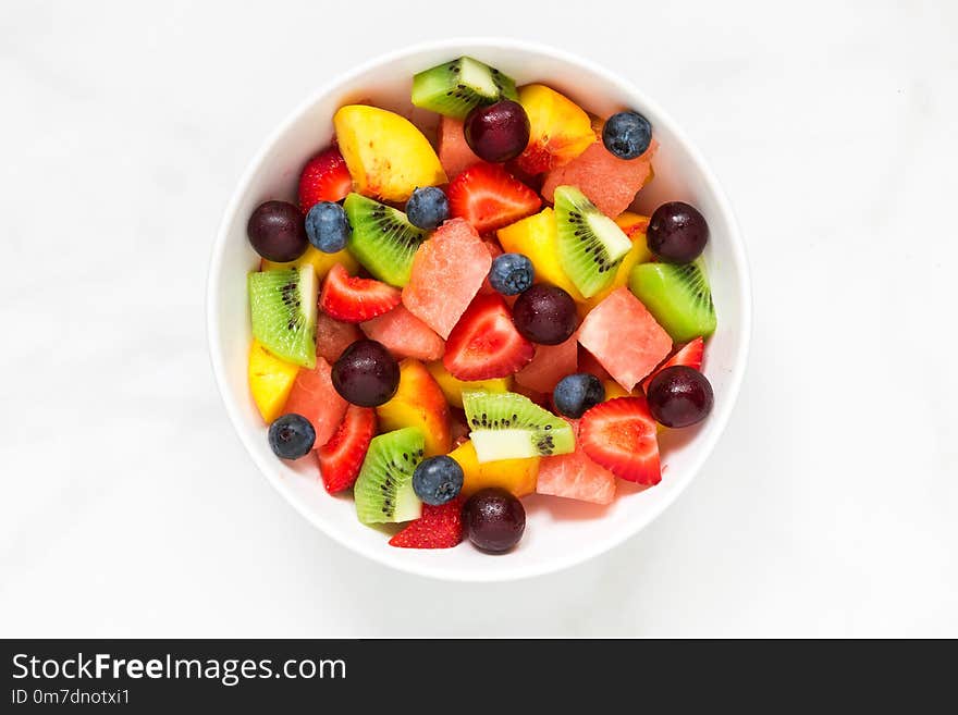 Bowl of healthy fresh fruit salad on white marble background. healthy food. top view.