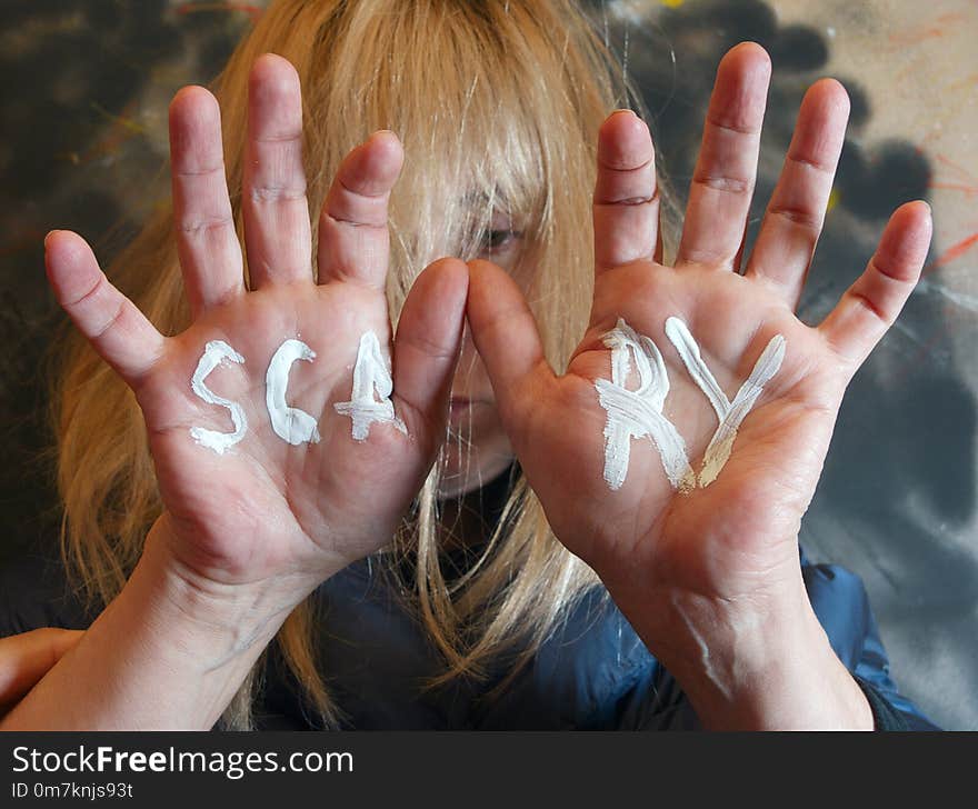 Selective focus portrait of a woman with hands in front of her face and a word Scary written on them. Selective focus portrait of a woman with hands in front of her face and a word Scary written on them