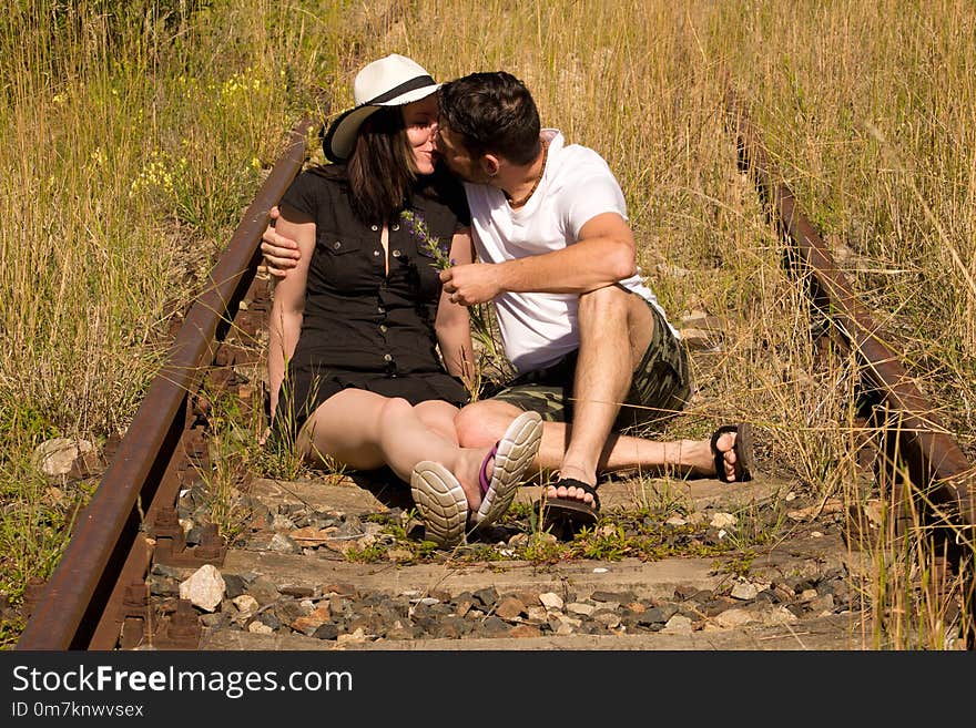 Man and women in straw hat and sunglasses. They sit on the rails on a sunny day. Man and women in straw hat and sunglasses. They sit on the rails on a sunny day.