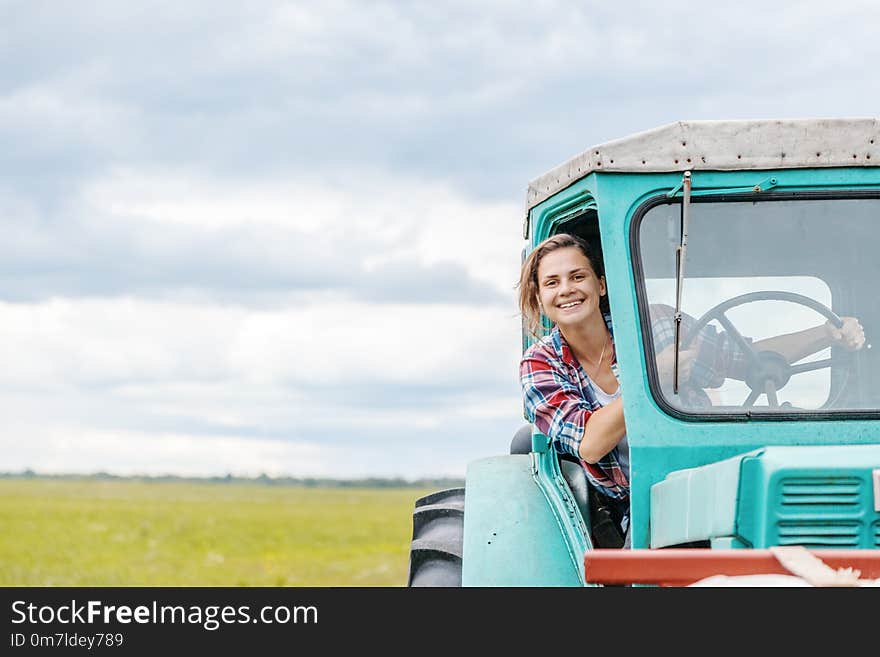 Young beautiful girl working on a tractor in the field, unusual