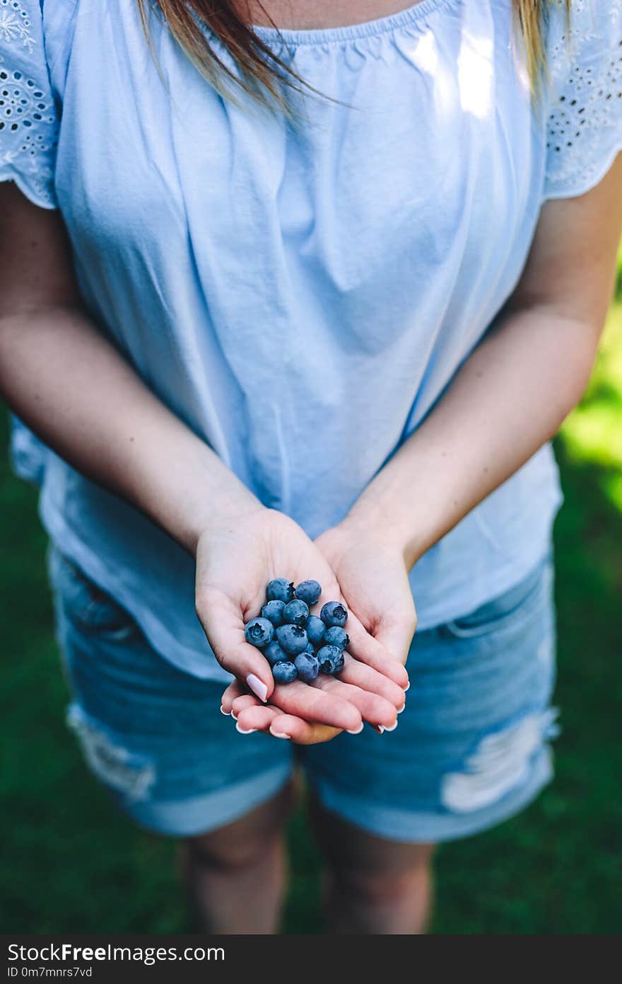 Woman holding blueberry fruits in her hands in the garden. Natural healthy foods.