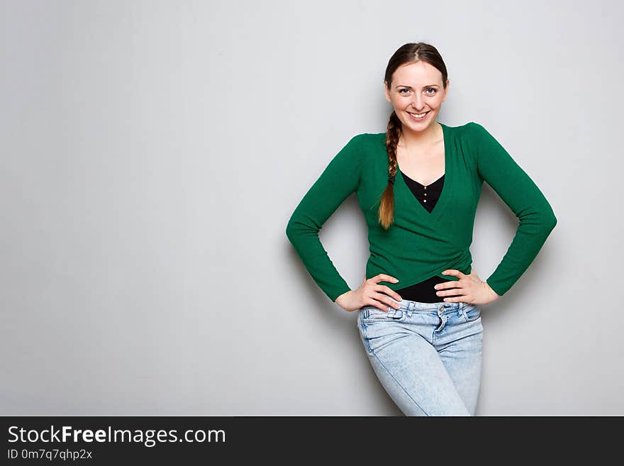 Smiling young woman standing by gray wall