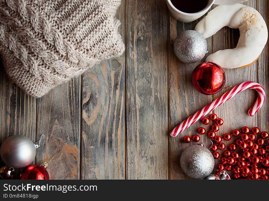 Festive christmas decor background. seasonal design with holiday adornments and embellishments. knitted sweater shiny balls beads and candy cane on grey wooden backdrop. Festive christmas decor background. seasonal design with holiday adornments and embellishments. knitted sweater shiny balls beads and candy cane on grey wooden backdrop.