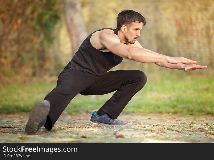 Young fitness man runner stretching legs before running