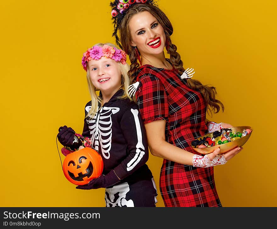 Smiling modern mother and daughter with Halloween candies