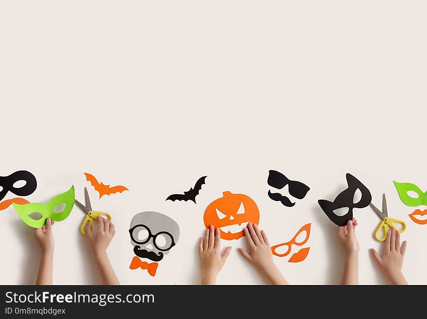 Halloween. The masks from paper on a white background which are cut out. Children`s hands. Halloween. The masks from paper on a white background which are cut out. Children`s hands.