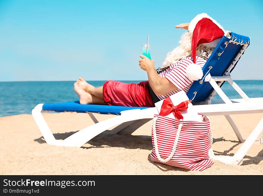 Authentic Santa Claus with cocktail resting on lounge chair at resort