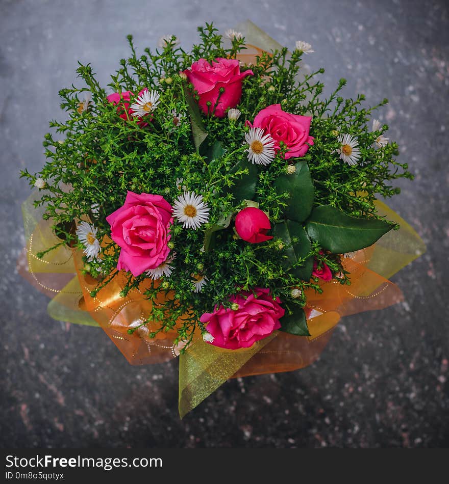 Beautiful Bouquet Of Red And White Flowers With Green Plants On A Black Stone Table. The View From The Top. Flat Lay.