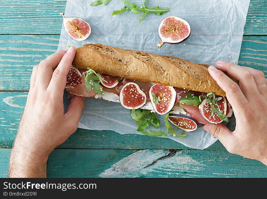 Outdoor man eating sandwich prosciutto mascarpone cheese figs to