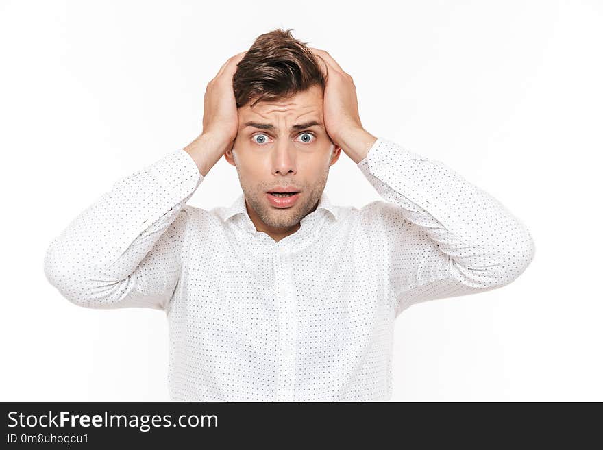 Portrait of irritated disappointed man 20s grabbing his head and expressing problem isolated over white background.