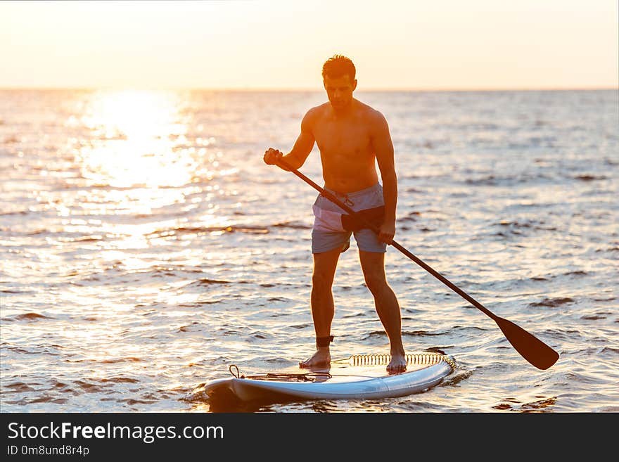 Image of young handsome man kayaking on lake sea.