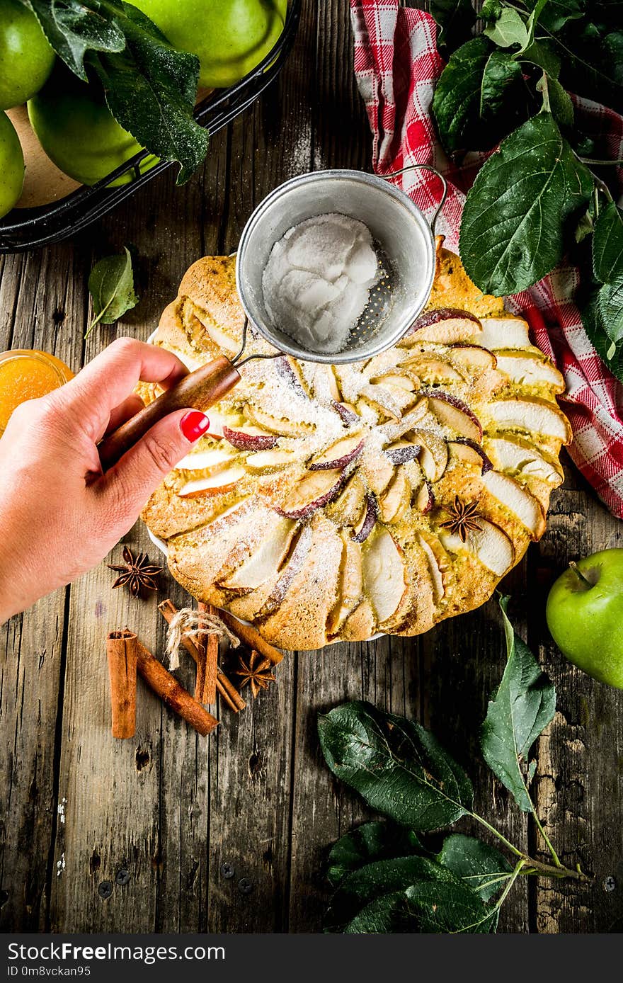 Homemade apple biscuit pie, sponge cake with red and green apples, on a wooden rustic table, with apples and leaves. Top view copy space