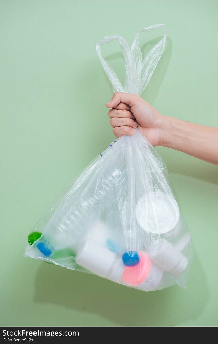 Female hand holding a waste bag isolated on white background.