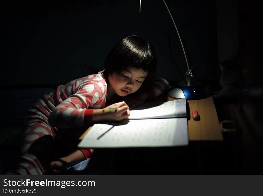 Portrait of little Asian girls doing her homework under the lighting lamp