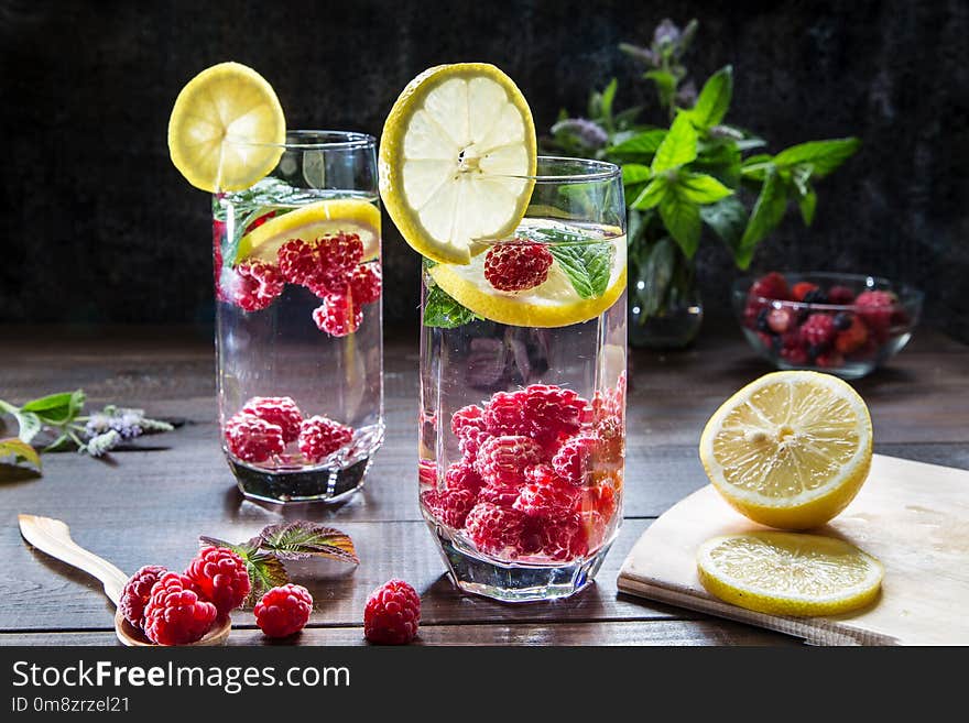 Refreshing drink with raspberries, lemon and mint on a dark background. Refreshing drink with raspberries, lemon and mint on a dark background.