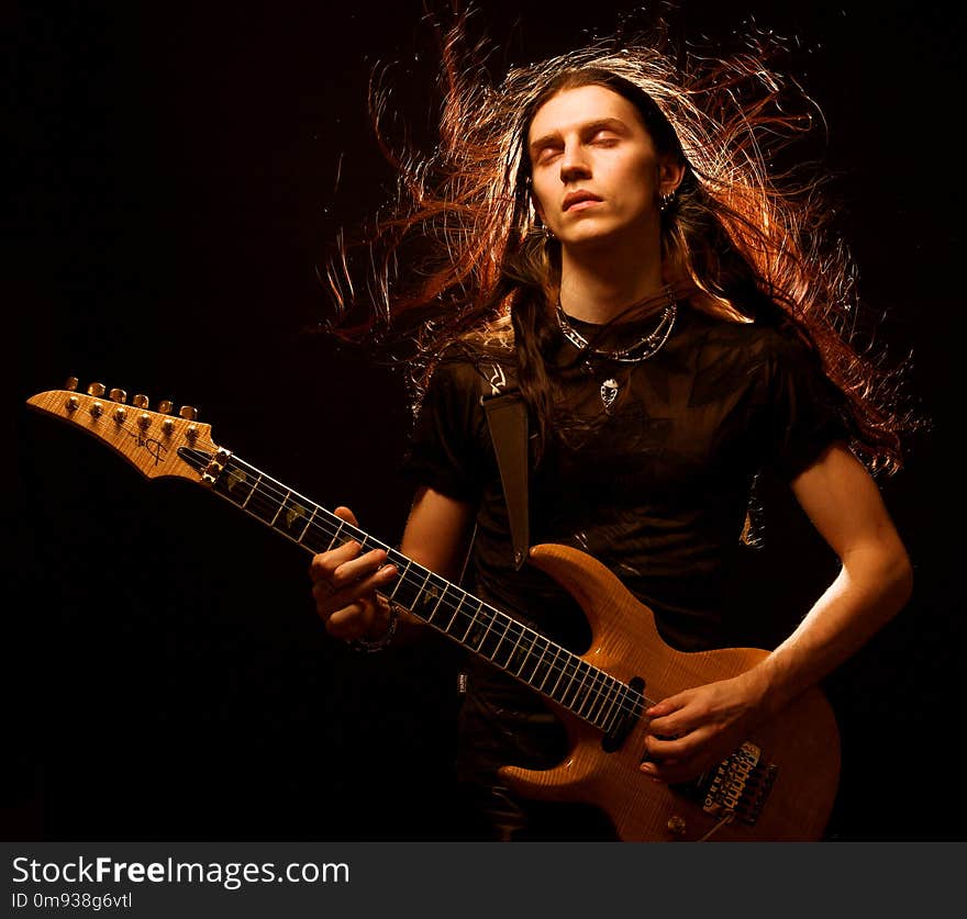 Man playing electrical guitar. wind in hair.