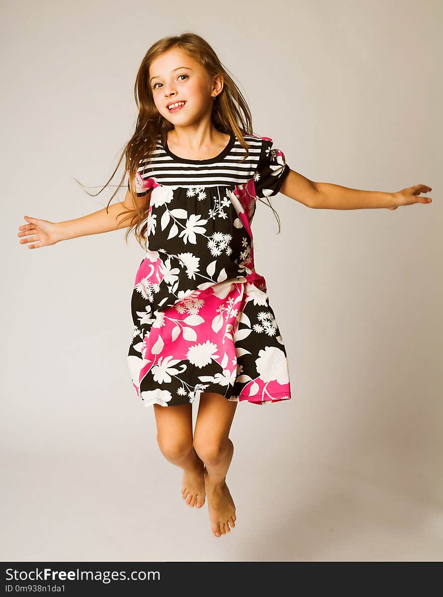 Little girl jumping of joy over grey background