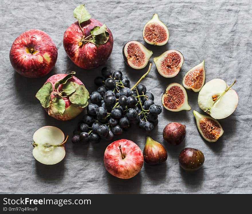 Seasonal autumn fruits - apples, grapes, figs on a gray background, top view. Flat lay