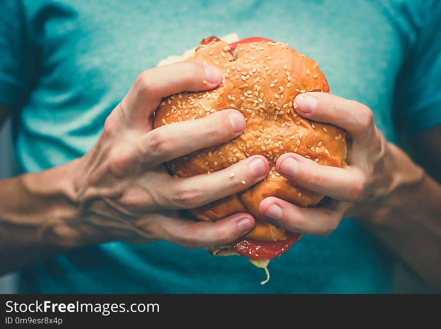 Big sandwich - hamburger burger with beef, cheese, tomato and tartar sauce in female hands. Big sandwich - hamburger burger with beef, cheese, tomato and tartar sauce in female hands