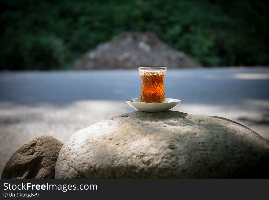 Eastern black tea in glass on a stone at forest. Eastern tea concept. Armudu traditional cup. Green nature background. Selective focus. Eastern black tea in glass on a stone at forest. Eastern tea concept. Armudu traditional cup. Green nature background. Selective focus