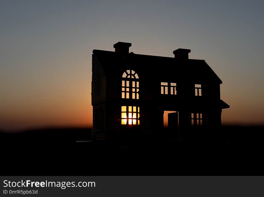 decorative small metallic house on the sunset background. Selective focus