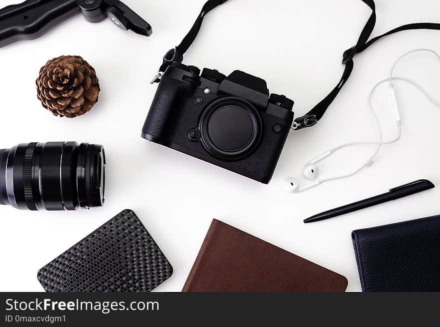 Top view desk workspace with hipster photo camera, lens, headphones, notepad for writing with black pen on white