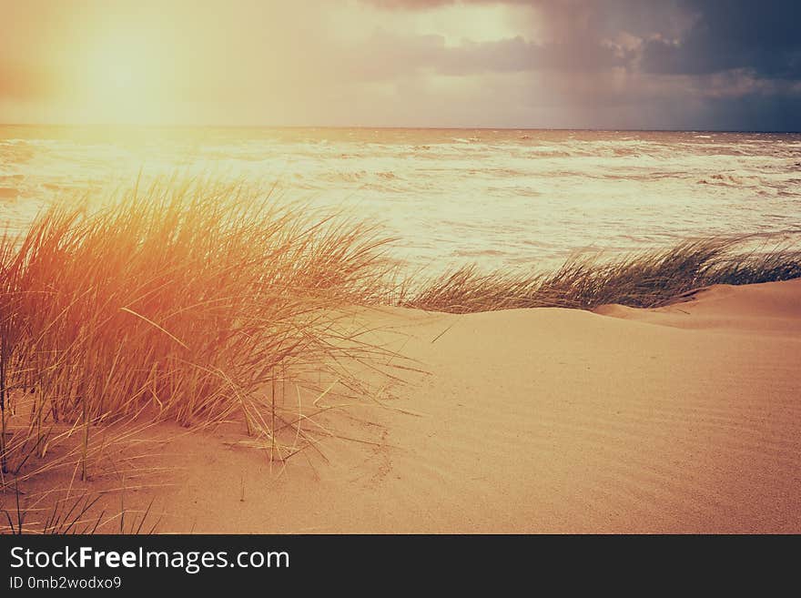 Pick elements of sun, sky, storm at a sea and sand dune, vintage style image - nature seascape background. Pick elements of sun, sky, storm at a sea and sand dune, vintage style image - nature seascape background