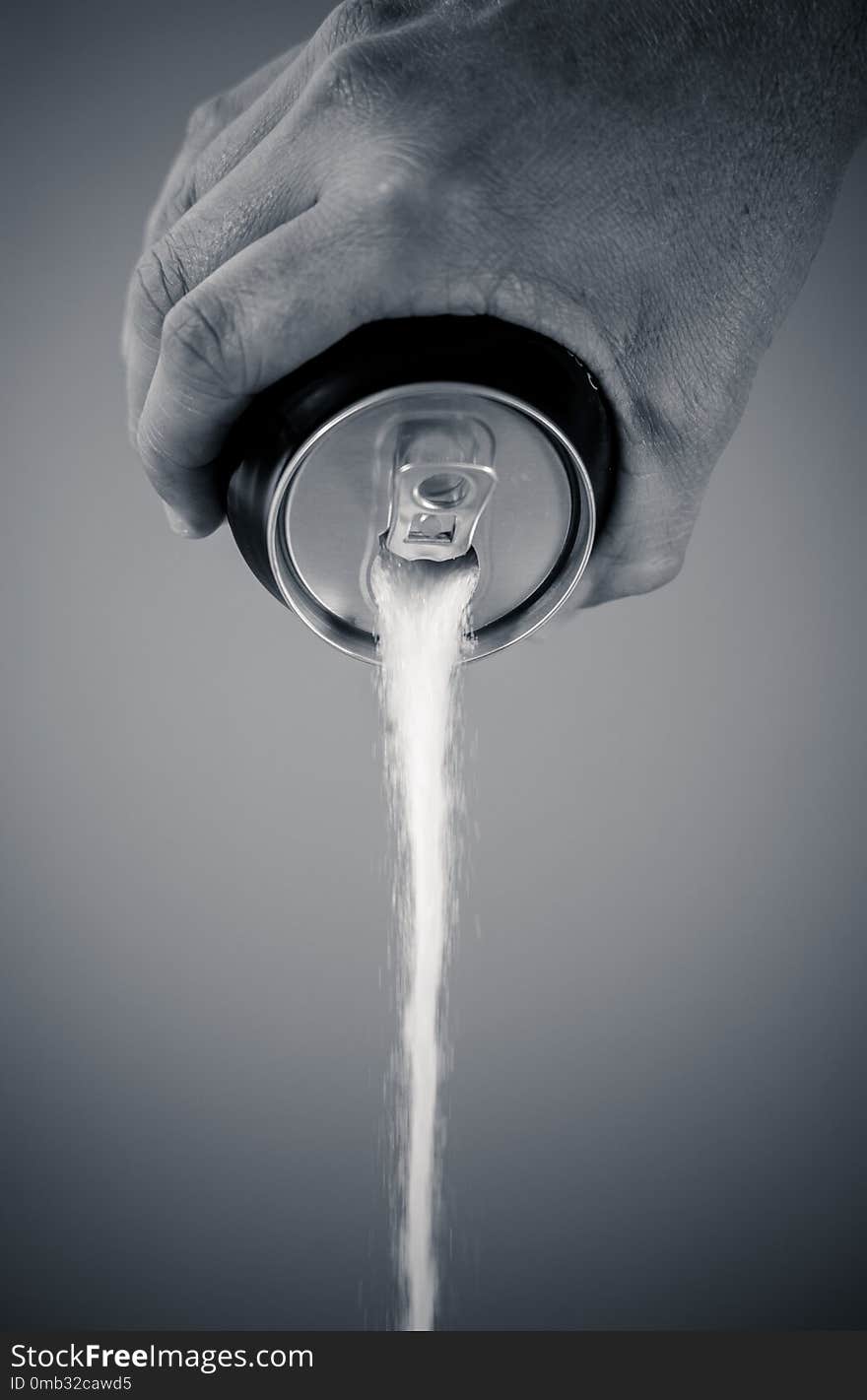 Black and withe portrait of a hand holding soda can pouring sugar in metaphor of sugar content of a refresh drink in healthy nutrition, diet, sweet and carbonated drinks addiction and unhealthy food concept. Black and withe portrait of a hand holding soda can pouring sugar in metaphor of sugar content of a refresh drink in healthy nutrition, diet, sweet and carbonated drinks addiction and unhealthy food concept.